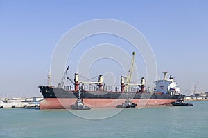 Vessel approaching to berth with tugs assistance. Mooring operations. Bulker. Dry cargo ship