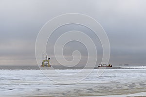 Vessel engaged in dredging at sunset time. Hopper dredger working at sea. Ship excavating material from a water environment