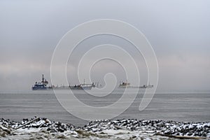 Vessel engaged in dredging at sunset time. Hopper dredger working at sea. Ship excavating material from a water environment