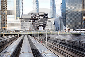 Vessel  TKA, a spiral staircase, with railroad and trains in front, skycrappers behind,  Hudson Yards, Manhattan`s West Side, NY