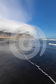 Vestrahorn mountain with cloud cover in Iceland, view from black sand beach