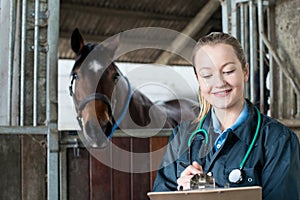 Female Vet Examining Horse In Stable