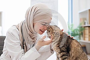 Vet in hijab fondling furry patient in exam room of clinic