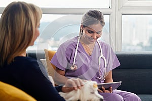 Vet Using Tablet Computer During House Call With Dog