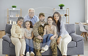 Portrait of happy military veteran together with his family sitting on sofa at home