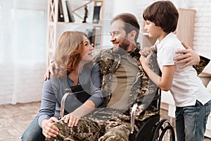 The veteran in a wheelchair came back from the army. A man in uniform in a wheelchair with his family.