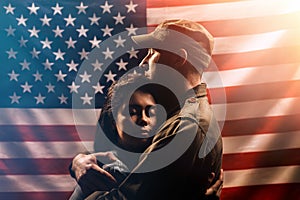 Veterans Day, Memorial Day. A soldier embraces his woman. Couple on the background of the American flag. The concept of the