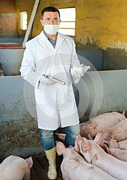 Veterinarian holding syringe and glass bottle