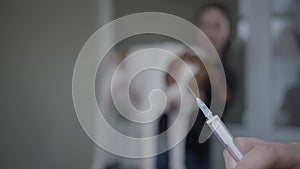 Veterinarian prepare a syringe for injection on the foreground. The blurred figure of woman petting her big dog standing