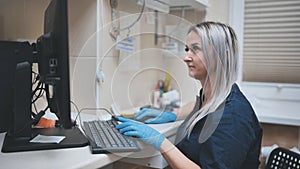 The veterinarian at work is typing on the keyboard at the computer.