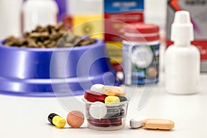 Veterinary pills or medication, pet medication, pet supplements or vitamins, with pet food in the background