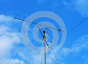 VHF radio antenna with stay ropes against cloudy blue sky photo