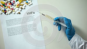 VHFs diagnosis written on paper, hand holding medication in syringe treatment