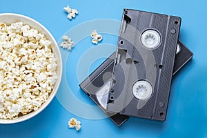 VHS tapes and popcorn on blue background.