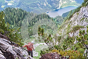 Via ferrata tourist looking down towards lake Gosau Gosauseen while climbing the via ferrata route called Intersport.