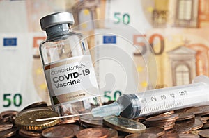 Vial of coronavirus Covid-19 vaccine and an hypodermic syringe sorrounded by euro coins and banknotes