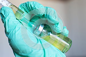 Vial filled with liquid vaccine in medical lab with syringe.doctor`s hand holds ampoule and syringe