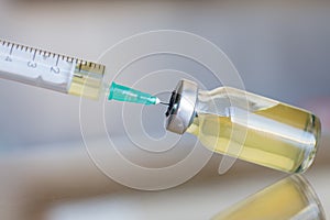 Vial filled with liquid vaccine in medical lab with syringe. medical ampoule and syringe on the glass surface