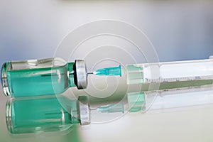 Vial filled with liquid vaccine in medical lab with syringe. medical ampoule and syringe on the glass surface