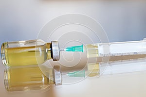 Vial filled with liquid vaccine in medical lab with syringe. medical ampoule and syringe on the glass surface
