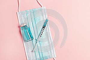 Vial vaccine, glass ampoules and a syringe with a medicine, medical protective mask on pink background. Gdobal