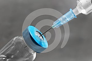 Vial with vaccine and syringe on grey background