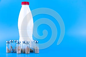 Vials, ampoules with dry probiotic, bifidobacteria and a bottle with milk on a blue background. Copy space