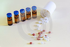 Vials of injectable drugs and scattered pills on the table