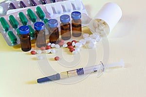 Vials of injectable drugs and scattered pills on the table. A syringe containing the flu virus vaccine