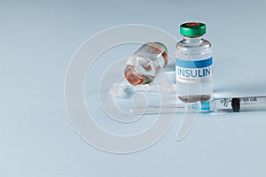 Vials of insulin with caplets and syringe on blue background with copy space