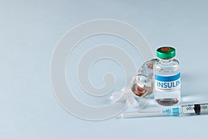 Vials of insulin with caplets and syringe on blue background with copy space