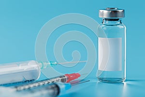 Vials of vaccine and syringes in a row on a blue background close-up photo