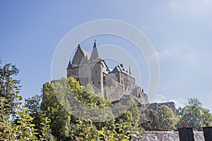Vianden Castle on a hill surrounded by trees with green foliage