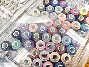Vibrant Array of Thread Spools in a Transparent Storage Box. Colorful thread spools neatly arranged in a clear plastic