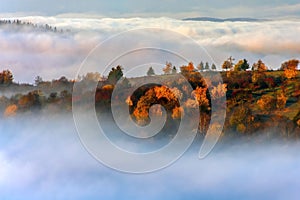 Vibrant autumn landscape with colorful trees hidden in clouds. Kremnica Mountains, Slovakia.