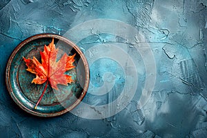 Vibrant Autumn Maple Leaf on Rustic Plate Against Textured Blue Background for Artistic Seasonal Concept