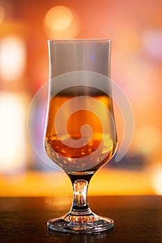 Vibrant Beer Glass with Frothy Foam on Orange Background