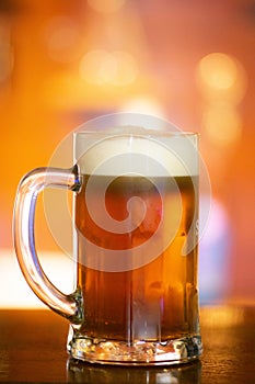 Vibrant Beer Glass with Frothy Foam on Orange Background