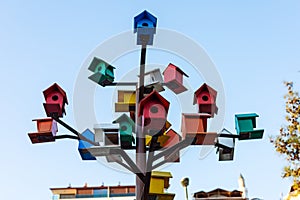 Vibrant birdhouses perched on a metal tree against the sky.