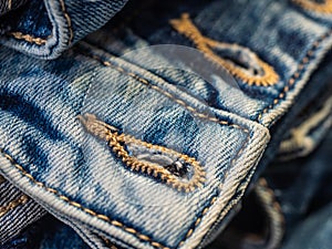 Vibrant blue close up image of waistband of denim jeans with double stitching and metal tack buttons