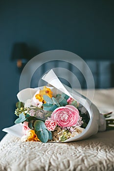 A vibrant bouquet of flowers resting on a neatly made bed, with the backdrop of a stylish bedroom setting