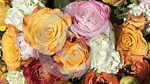 Vibrant bouquet of flowers with yellow-orange roses  pink and orange buttercups  white guilder roses