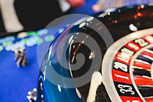 Vibrant casino table with roulette in motion, with casino chips, tokens, the hand of croupier, dollar money and a group of