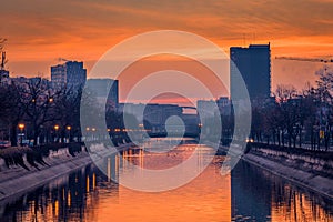 Vibrant cityscape shot early morning before sunrise in Bucharest with a river in the foreground with ducks swimming