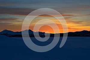 Vibrant colourful dawn sky sunset over mountain in winter with tromsoe city island