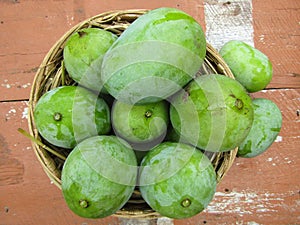 Vibrant display of fresh green mangos in a woven basket