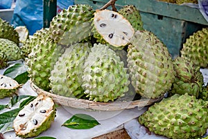 A vibrant display of fresh soursops, one cut open revealing the juicy interior, at an outdoor market photo