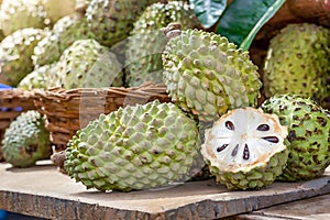 A vibrant display of fresh soursops, one cut open revealing the juicy interior, at an outdoor market photo