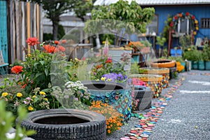 A vibrant eco-friendly garden path adorned with colorful upcycled tires as planters, leading to a quaint blue shed