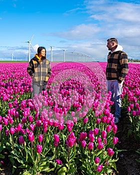 In a vibrant field of purple tulips in the Netherlands, two people stand enchanted by the beauty of Spring, surrounded